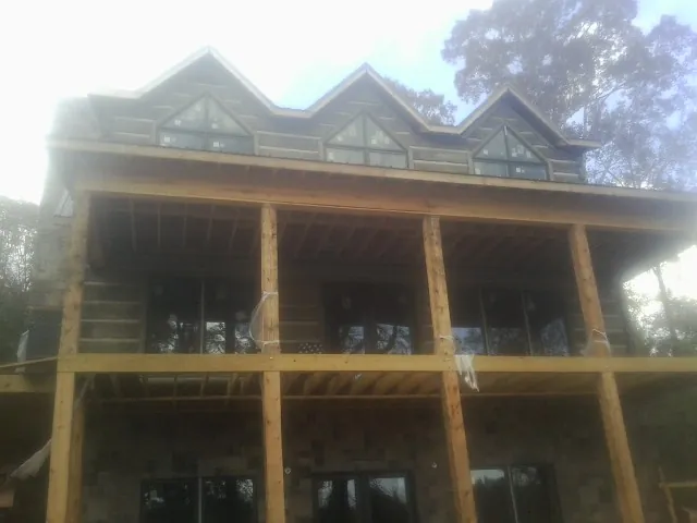 Dormers and porch framing on a large log home under construction — Roof Coating work by our crew in Livingston