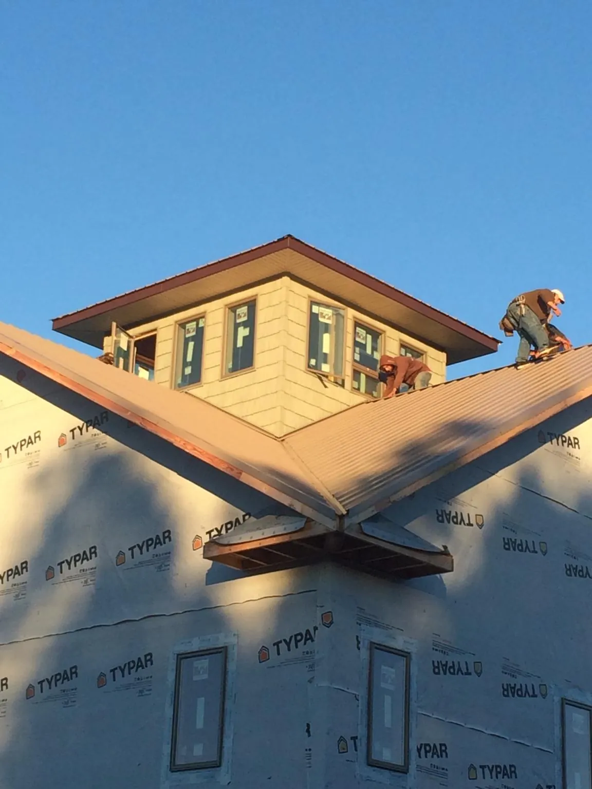 Roofers working around a rooftop cupola on a new metal roof at sunset — Roof Waterproofing in Livingston by Roofing Brothers